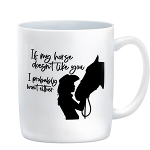 May include: White ceramic mug with a black silhouette of a horse and a person wearing a cowboy hat. The text on the mug reads "If my horse doesn't like you, I probably won't either."