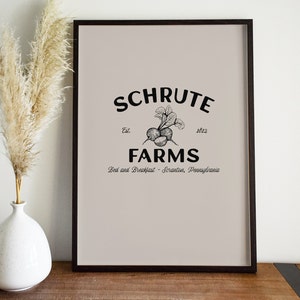 Könnte beinhalten: Ein gerahmter Druck mit beigefarbenem Hintergrund und schwarzem Text, der "Schrute Farms Est. 1912 Bed and Breakfast - Scranton, Pennsylvania" lautet. Eine Schwarzweißillustration einer Rübenpflanze befindet sich in der Mitte des Textes.