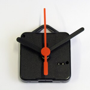Peut inclure: Aiguilles d'horloge noires avec une aiguille des secondes rouge. Les aiguilles sont fix&eacute;es &agrave; un m&eacute;canisme d'horloge carr&eacute; noir.