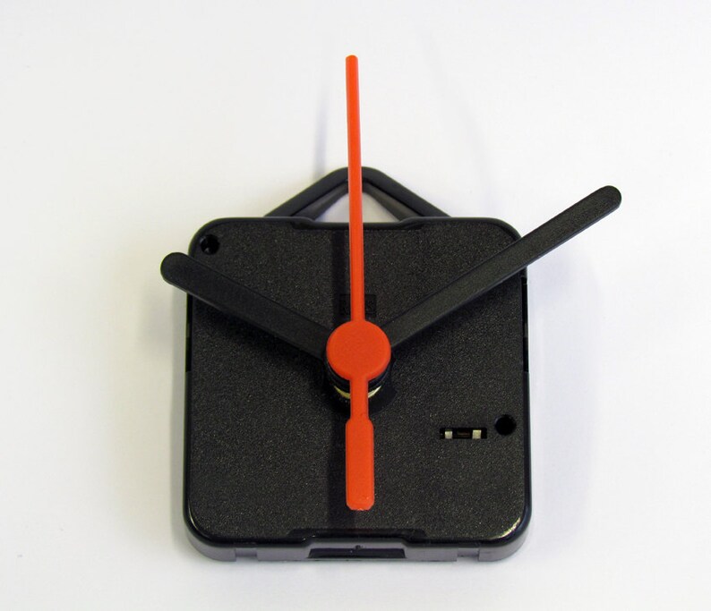 Peut inclure: Aiguilles d'horloge noires avec une aiguille des secondes rouge. Les aiguilles sont fix&eacute;es &agrave; un m&eacute;canisme d'horloge carr&eacute; noir.