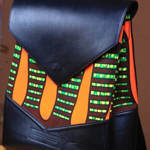 May include: A black leather backpack with a flap closure. The backpack has a colorful patterned fabric lining with orange, green, and brown stripes. The brand name "Honey & Milo" is printed on the front of the bag.