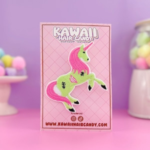 Puede incluir: Un parche de hierro de unicornio zombie rosa y verde con el texto "Kawaii Hair Candy" y una direcci&oacute;n de sitio web.