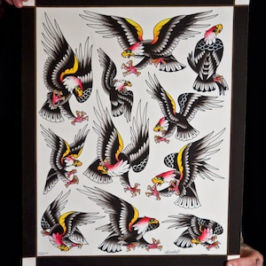 May include: A black and white print of a traditional tattoo design featuring multiple eagles in various poses. The eagles are depicted with red, yellow, and black accents. The print is signed "Krendall's" in the bottom right corner.