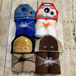 May include: Four hooded towels featuring Star Wars characters. The towels are folded and tied with ribbon. The characters are R2-D2, C-3PO, Chewbacca, and a Stormtrooper.