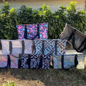 K&ouml;nnte beinhalten: Acht verschiedene gemusterte Tragetaschen mit schwarzen Griffen. Die Taschen sind in einer Reihe auf dem Boden angeordnet. Die Taschen sind aus strapazierf&auml;higem Stoff gefertigt und haben eine Vielzahl von Designs, darunter florale, geometrische und abstrakte Muster.