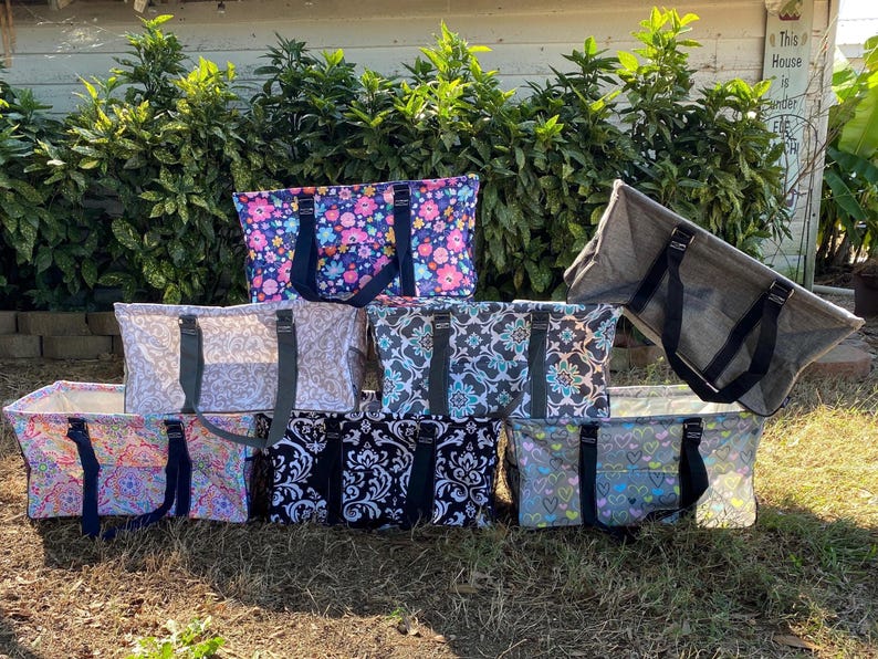 K&ouml;nnte beinhalten: Acht verschiedene gemusterte Tragetaschen mit schwarzen Griffen. Die Taschen sind in einer Reihe auf dem Boden angeordnet. Die Taschen sind aus strapazierf&auml;higem Stoff gefertigt und haben eine Vielzahl von Designs, darunter florale, geometrische und abstrakte Muster.
