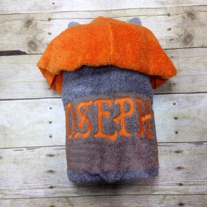 May include: Gray hooded towel with an orange hood and the name "JOSEPH" embroidered in orange on the front.
