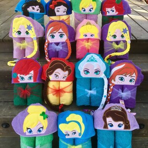 May include: A collection of 14 hooded towels featuring different Disney princess characters. Each towel is made of soft, absorbent material and features a colorful embroidered design of a princess's face. The towels are arranged in two rows, with each row containing seven towels.