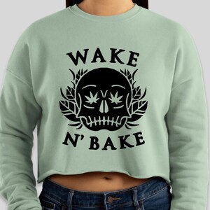 May include: A light green cropped sweatshirt with a black skull graphic and the text "WAKE N' BAKE".