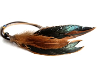 May include: A brown and black feather headband with beads. The feathers have a iridescent green sheen.