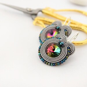 May include: A pair of silver earrings with iridescent crystal beads and a silver hook closure.
