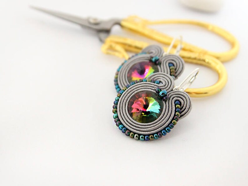 May include: A pair of silver earrings with iridescent crystal beads and a silver hook closure.