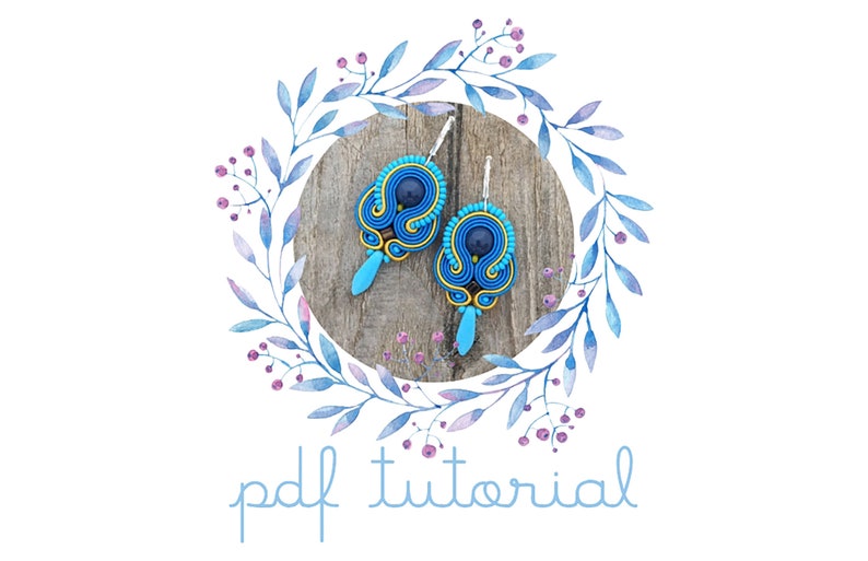 Pode incluir: Um tutorial em PDF para fazer brincos azuis e amarelos com uma conta azul escura no centro. Os brincos s&atilde;o exibidos em uma superf&iacute;cie de madeira com uma coroa de flores aquarela ao redor.