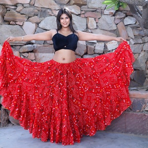 May include: A red, multi-layered skirt with a white and orange floral print. The skirt is flowing and has a ruffled hem.