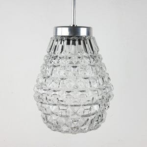May include: A clear glass pendant light fixture with a silver metal top. The glass is textured with a diamond pattern.