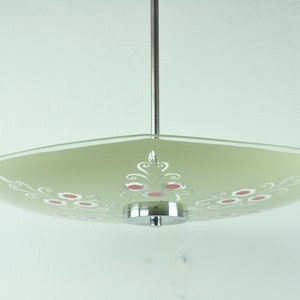 May include: A green glass ceiling light fixture with a white and red floral design. The light fixture has a chrome finish and a round canopy.