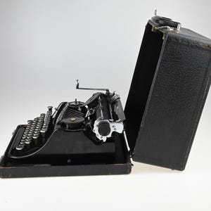 May include: A white ceramic mug with a black handle and the text "But First, Coffee" in a bold, black font. The mug is sitting on a wooden surface. The mug is approximately 4 inches tall.