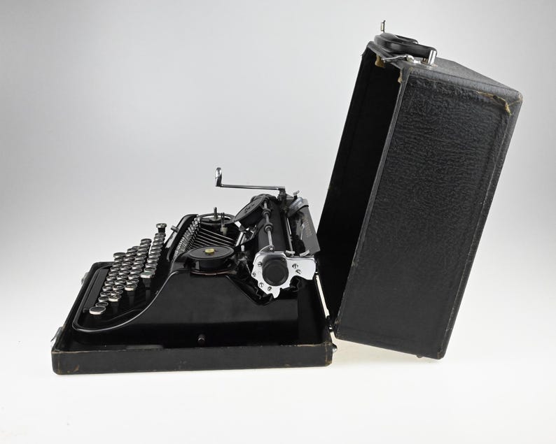 May include: A white ceramic mug with a black handle and the text "But First, Coffee" in a bold, black font. The mug is sitting on a wooden surface. The mug is approximately 4 inches tall.