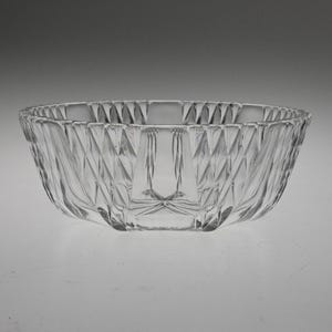 May include: A clear glass bowl with a geometric pattern. The bowl is round and has a wide rim.