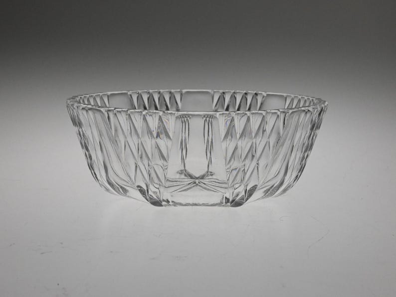 May include: A clear glass bowl with a geometric pattern. The bowl is round and has a wide rim.