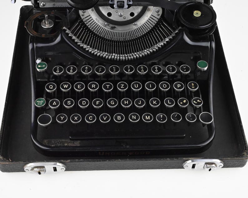 May include: A black Underwood Model X10 typewriter with a QWERTY keyboard layout. The typewriter has round, white keys with black lettering and a silver carriage. The machine sits in a black case with silver latches.