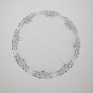 May include: A clear glass cake plate with a decorative, scalloped edge.