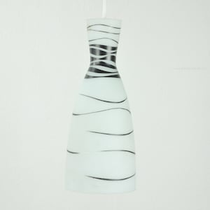 May include: White glass pendant light with black wavy lines. The light is shaped like a bottle.