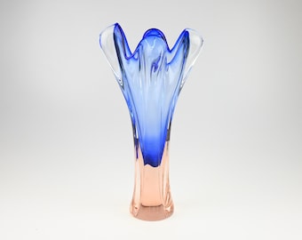Può includere: Un vaso di vetro alto ed elegante con la parte superiore svasata. Il vaso presenta una sfumatura di colori, che passa da un color pesca chiaro alla base a un blu vibrante nella parte superiore. Il design ricorda un fiore.