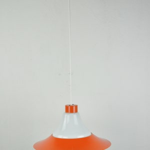 May include: A white and orange pendant light with a white cord hanging from the ceiling.