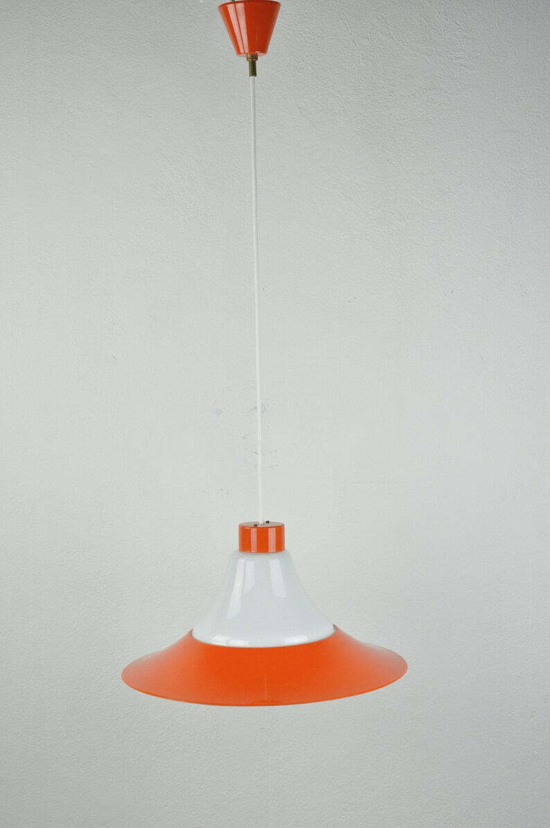 May include: A white and orange pendant light with a white cord hanging from the ceiling.