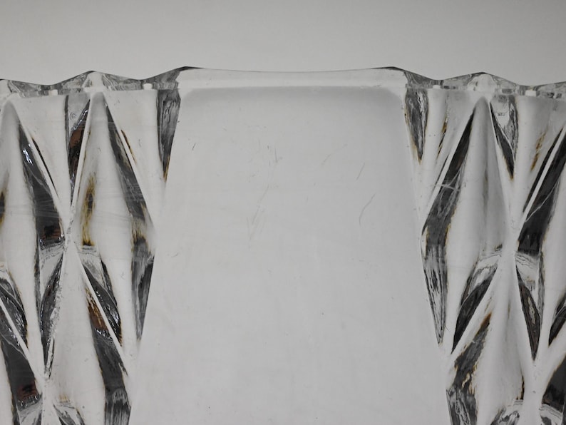 May include: Close-up of the top edge of a clear glass bowl with a diamond-shaped pattern.