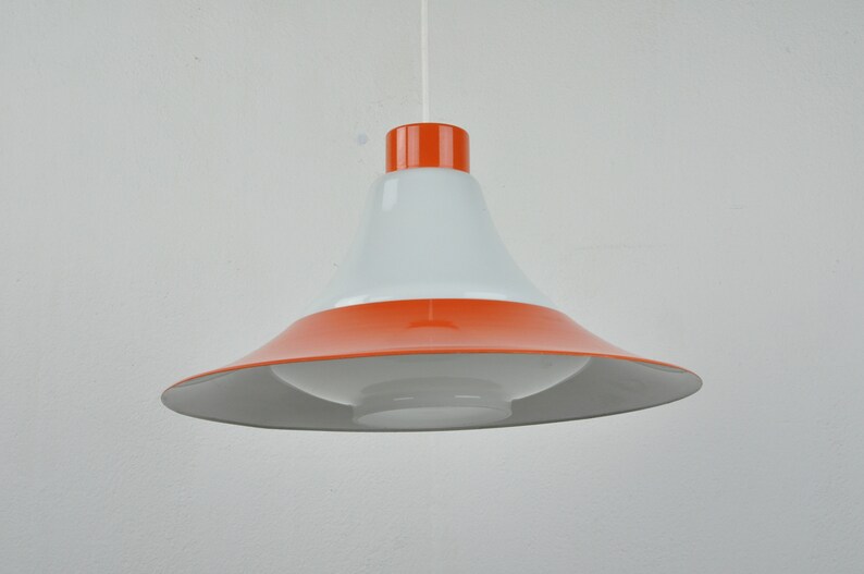 May include: A white and orange pendant light with a wide, flared shade. The shade is white on the inside and orange on the outside.
