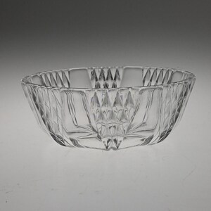 May include: A clear glass bowl with a diamond-shaped pattern. The bowl is empty and has a smooth, polished surface.