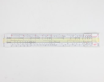 May include: A white Logarex slide rule featuring a central yellow strip with black numerical scales and markings. The device includes a clear plastic cursor with a red hairline, and the text Logarex 27204 is printed on the right side.