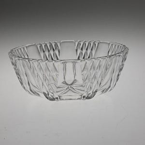 May include: A clear glass bowl with a diamond pattern. The bowl is round and has a wide rim.