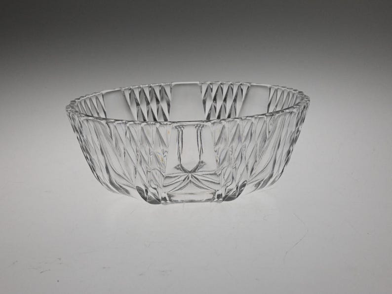 May include: A clear glass bowl with a diamond pattern. The bowl is round and has a wide rim.