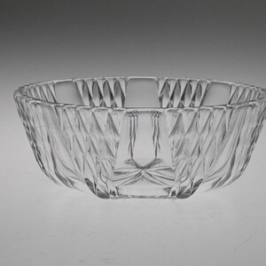 May include: A clear glass bowl with a decorative, faceted design. The bowl has a wide, round shape and a smooth, polished finish.