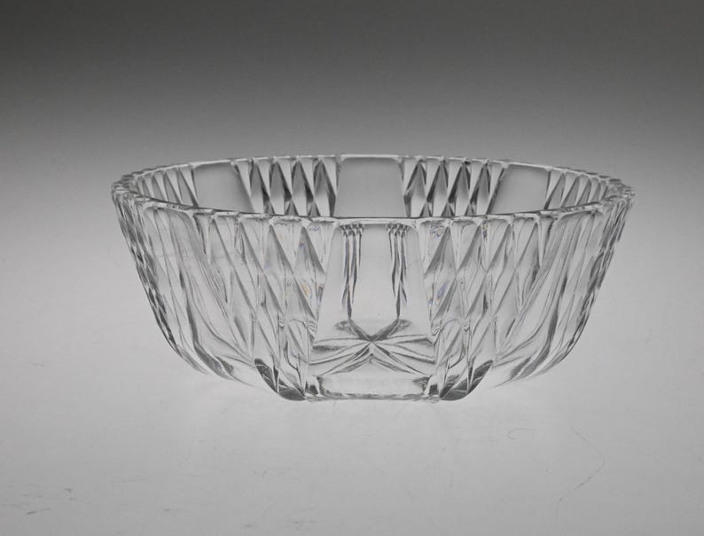 May include: A clear glass bowl with a decorative, faceted design. The bowl has a wide, round shape and a smooth, polished finish.