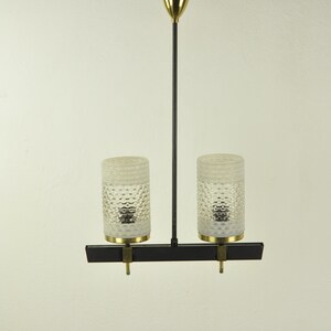 May include: A black and brass two-light pendant light fixture with frosted glass shades.
