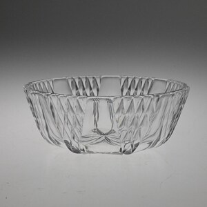 May include: A clear glass bowl with a decorative, diamond-shaped pattern. The bowl is round and has a wide, shallow shape.