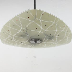 May include: A vintage, mid-century modern pendant light fixture. The light has a pale green, saucer-shaped shade with a white grid pattern and small red and black dots. The fixture is suspended from a black cord and has a chrome base.