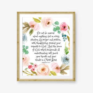 Puede incluir: Impresión enmarcada con un marco dorado, que muestra una corona floral en tonos rosa pálido, melocotón y azul. El texto dice: «No se preocupen por nada...» de Filipenses 4:6-7. El diseño de acuarela añade un toque de elegancia.