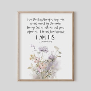 May include: A framed print featuring the text "I am the daughter of a King, who is not moved by the world. For my God is with me and goes before me. I do not fear because I AM HIS. 2 Corinthians 6:18." The print has a watercolor floral design in soft pastel colors.