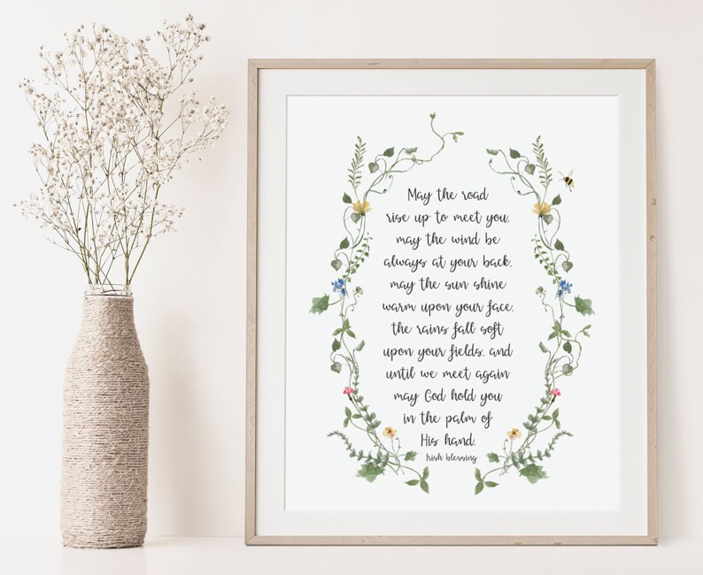 May include: A white printable art print with a floral border and a poem that reads: "May the road rise up to meet you. May the wind be always at your back. May the sun shine warm upon your face. The rains fall soft upon your fields, and until we meet again may God hold you in the palm of His hand. Irish Blessing"