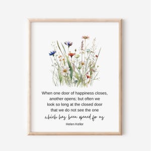 May include: A framed print featuring a watercolor illustration of wildflowers in shades of blue, red, and white. The print includes a quote by Helen Keller: "When one door of happiness closes..."