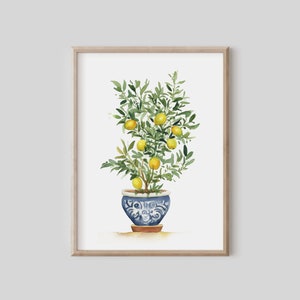 May include: Watercolor painting of a lemon tree in a blue and white patterned pot. The tree is full of green leaves and yellow lemons. The artwork is framed in a light brown wooden frame, perfect for home decor.