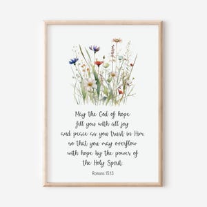 Könnte beinhalten: Ein Aquarellbild von Wildblumen vor weißem Hintergrund mit einem Rahmen. Das Bild enthält den Text "May the God of hope fill you with all joy and peace as you trust in Him. so that you may overflow with hope by the power of the Holy Spirit. Romans 15:13"
