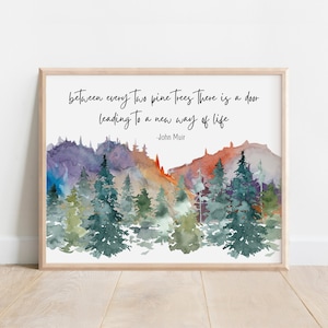 May include: A framed art print featuring a watercolor landscape with pine trees and mountains in shades of green, purple, and orange. The quote "between every two pine trees there is a door leading to a new way of life" by John Muir is written in black.
