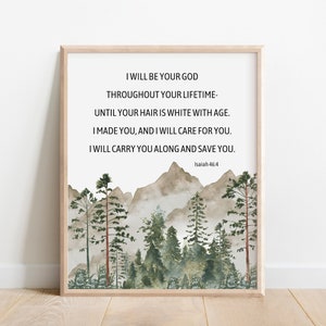 Puede incluir: Un estampado enmarcado con un paisaje de acuarela de montañas y árboles en tonos verdes y marrones. El estampado incluye el texto "I WILL BE YOUR GOD..." de Isaías 46:4, en una fuente sencilla. El marco es de color madera clara.