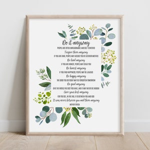 Könnte beinhalten: Ein gerahmter Kunstdruck mit dem Gedicht Do it anyway von Mutter Teresa in schwarzer Schrift. Das Design ist mit Aquarellillustrationen von grünen Eukalyptusblättern und kleinen gelben Beeren verziert, die den zentralen Textblock umgeben.